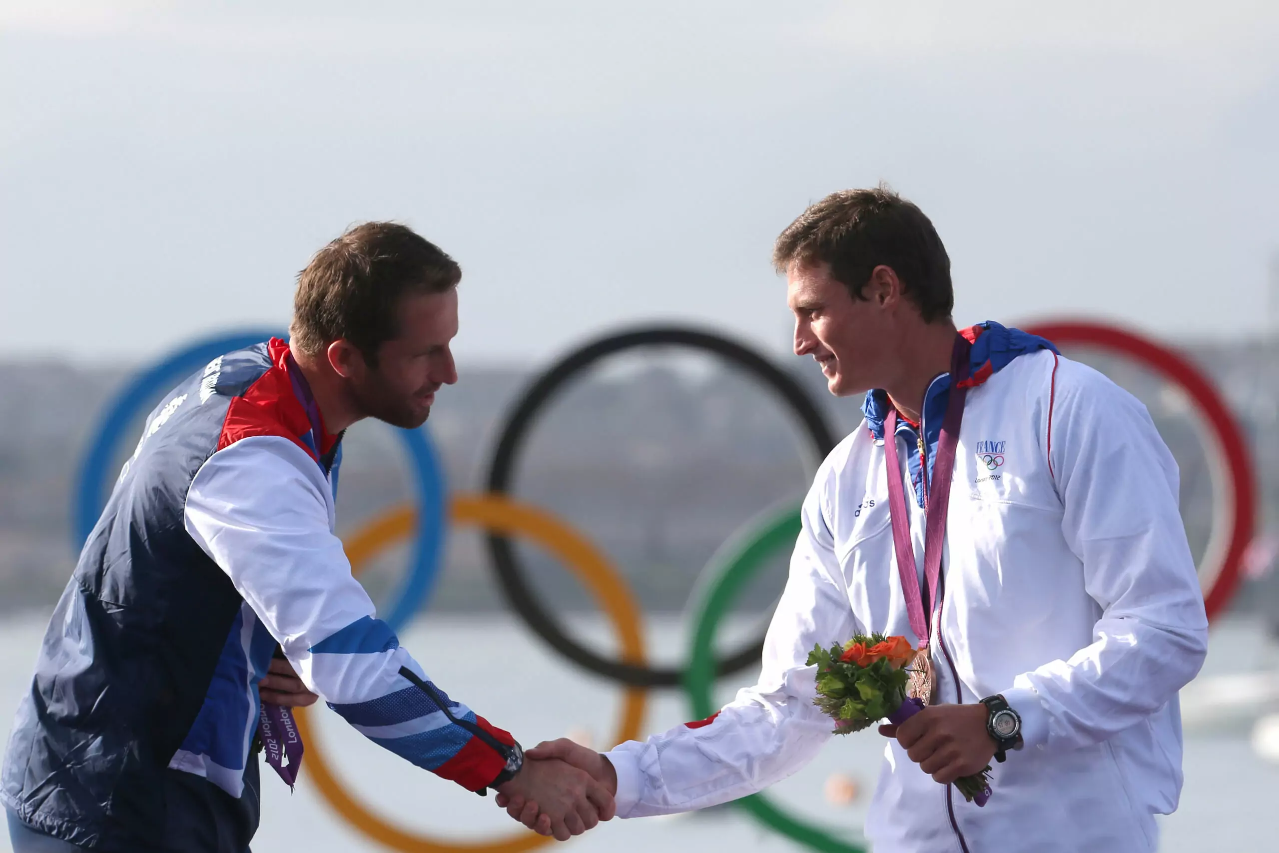 Jonathan Lobert shaking hands with his opponent on the London 2012 Olympic podium, symbolizing respect and sportsmanship